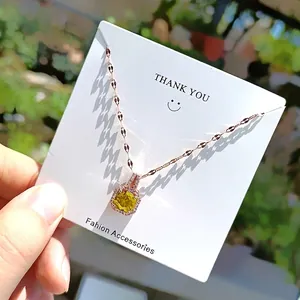 Detail view of square yellow gemstone necklace with rose gold chain on a brand card