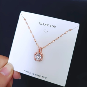 Detail view of rose gold necklace with square zircon pendant on display card