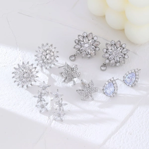 Détails de cinq boucles d'oreilles argentées fleur et feuille avec zircons bleus incrustés