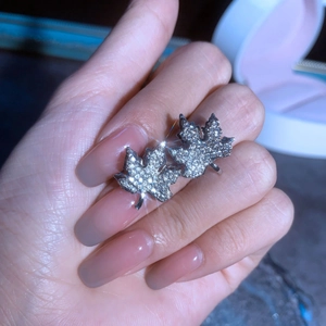 Gros plan détaillé de boucles d'oreilles feuille d'érable en argent serties de zircons