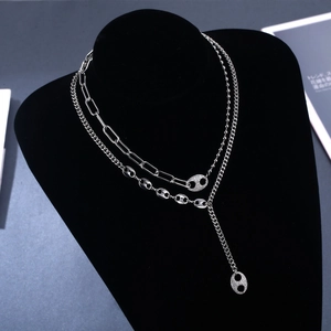 Détail d'un collier multicouche argenté avec chaîne trombone et fermoir nez de porc en zircon