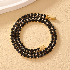 Makro-Detail einer minimalistischen Tennis-Kette mit schwarzen Zirkoniasteinen und Vergoldung