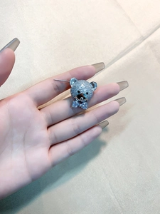 Detailed view of silver teddy bear earrings featuring pavé cubic zirconia and bow ties