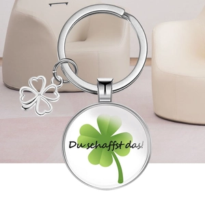 Silver four-leaf clover keychain with 'Du schaffst das!' motivational glass pendant