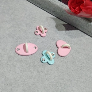 Pink heart and flower shoe charms with rhinestones on a textured grey surface