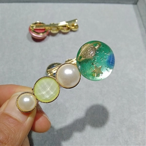 Vue détaillée de la sphère en résine planétaire avec perles sur barrette dorée