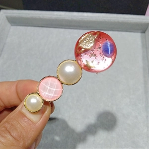 Détail d'une pince à cheveux thème étoilé avec résine rose et perles de nacre