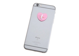 Pink heart-shaped phone grip hook with gold lettering on a silver smartphone case