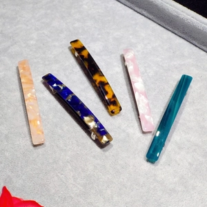 Set of five tortoiseshell acetate spring hair clips in various patterns on a grey velvet tray