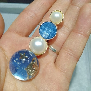Détail d'une pince à cheveux ciel étoilé avec sphères en résine bleue et étoiles