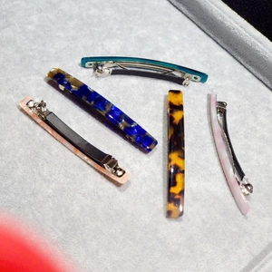 Detail view of five acetate leopard print hair clips on a gray velvet jewelry display tray
