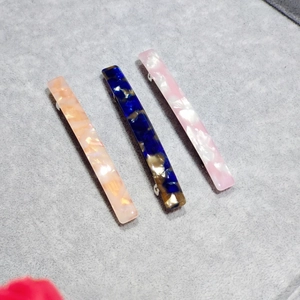 Close-up of three leopard marble acetate hair clips on a grey velvet surface