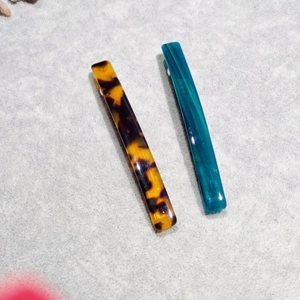 Detail view of rectangular leopard print and turquoise acetate hair clips on fabric