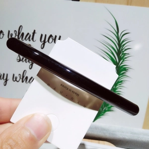 Détail d'une pince à cheveux noire minimaliste en résine avec une finition brillante