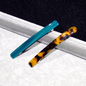 Detailed close-up of blue and tortoiseshell acetate hair clips on display stand