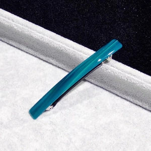 Close-up of 8cm dark teal acetate hair clip with leopard texture on a gray velvet tray