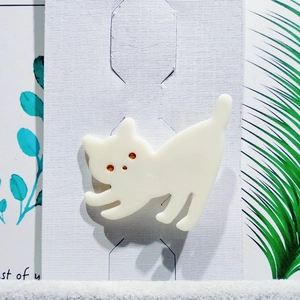Makro-Detail einer süßen weißen Katzen-Haarspange aus Acryl auf einer Display-Karte