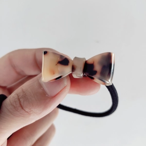 Close-up of leopard pattern bow scrunchie with elastic fabric and resin hair tie detail