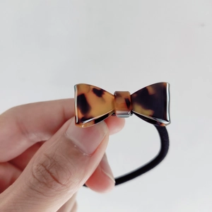 Detail showing tortoiseshell pattern bow scrunchie with high elasticity black rubber band