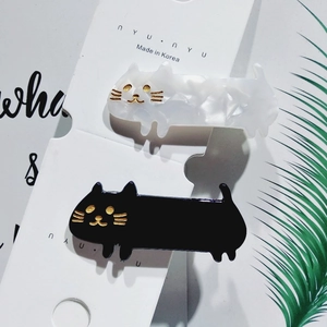 Detail of cat-shaped acetate hair clips in black and white marble on display card