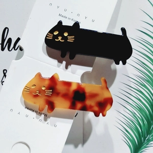 Detail of acetate cat hair clips in black and tortoiseshell pattern with gold accents