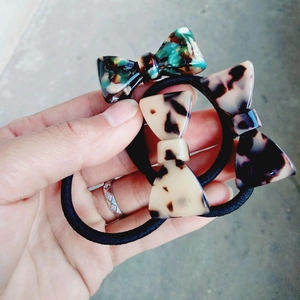 Close-up of three leopard and marble pattern bow hair ties held in hand for detail