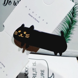 Close-up of black acetate cat hair clip with gold whiskers on a branded white card