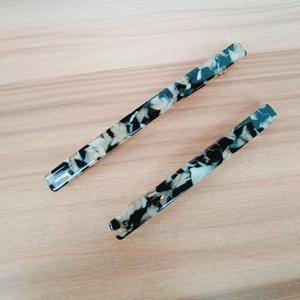 Detailed macro view of two minimalist marble pattern hair clips on a light wood background