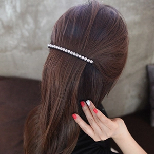 Elegant Korean style black hair clip with white pearls worn on long brown hair