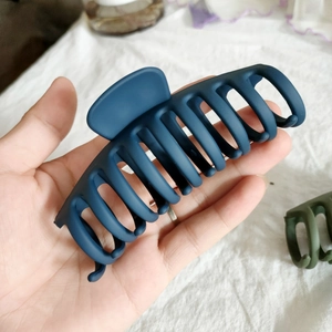 Détail d'une grande pince à cheveux bleu foncé mat avec mécanisme de préhension denté