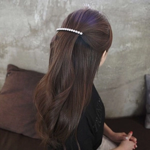 Close-up of minimalist black spring hair clip with white pearls on brown wavy hair
