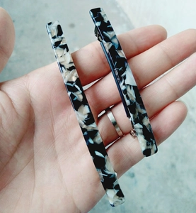 Detail of marble pattern acetate hair clips with silver metal closure on hand