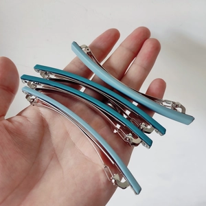 Lot de quatre barrettes mates de 10 cm en tons bleus tenues en main pour la taille