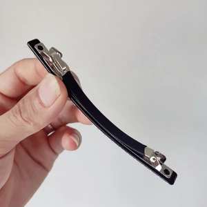 Detailed close-up of a sleek black spring hair clip with a durable silver metal base