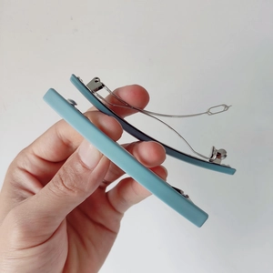 Détail de pinces à cheveux bleu mat montrant le mécanisme de ressort en métal durable