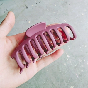 Grande pince à cheveux mate violet foncé tenue à la main pour montrer la taille réelle