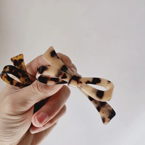 Macro view of brown tortoiseshell bow hair clips with glossy acetate finish