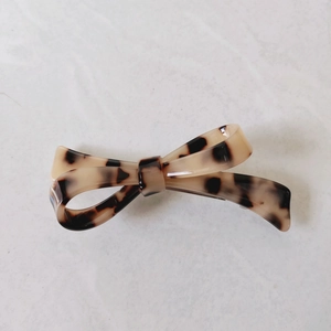 Detail of a minimalist hair clip with a leopard print bow design and glossy finish