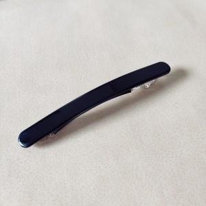 Close-up of a sleek black curved hair clip with silver metal spring fastener detail