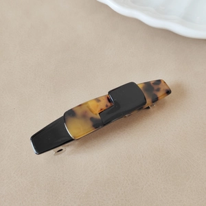 Detail of tortoiseshell and black acetate hair clip with silver metal spring buckle