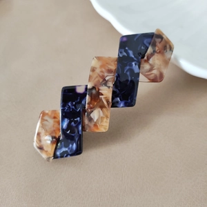 Detailaufnahme der geometrischen Haarspange aus Acetat mit Bernstein- und Marmormuster