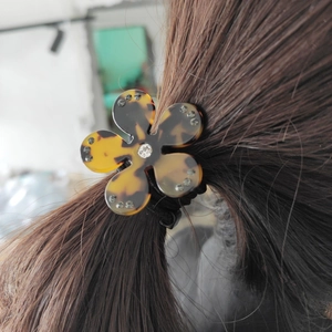 Détail de l'élastique à cheveux fleur léopard avec texture écaille et strass brillants
