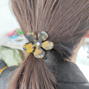 Vue détaillée d'un chouchou fleur à motif léopard avec strass sur une queue de cheval
