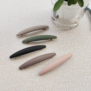 Close-up of five matte earth-toned Morandi spring hair clips on a soft beige fabric