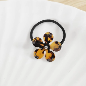 Détail de l'élastique à cheveux fleur léopard avec strass sur surface ondulée