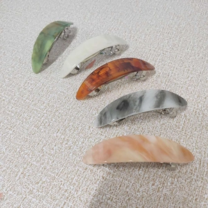 Close-up of five marble texture acetate hair clips with durable metal spring base