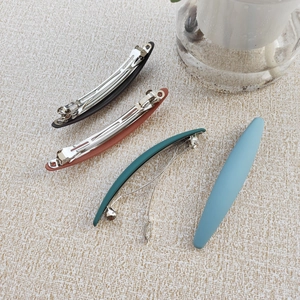 Macro detail of four matte Morandi-colored spring hair clips on a textured surface