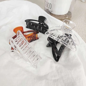 Pinces à cheveux géométriques minimalistes en ambre, noir et transparent sur tissu blanc