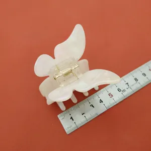 Vue détaillée d'une pince à cheveux papillon blanc iridescent avec ressort doré