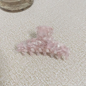Dettaglio della pinza per capelli in acetato rosa traslucido con finitura marmorizzata